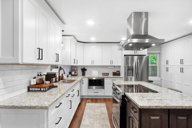 kitchen with a sink, island exhaust hood, dark wood-type flooring, decorative backsplash, and appliances with stainless steel finishes