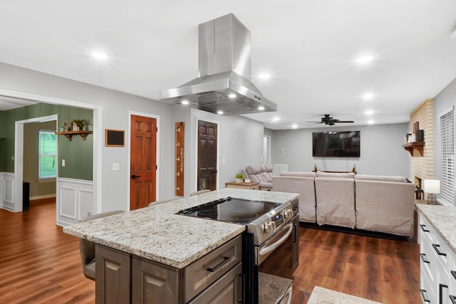kitchen with light stone countertops, dark wood-style flooring, ceiling fan, stainless steel electric stove, and island exhaust hood