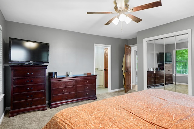 bedroom with a closet, ensuite bath, light carpet, and baseboards