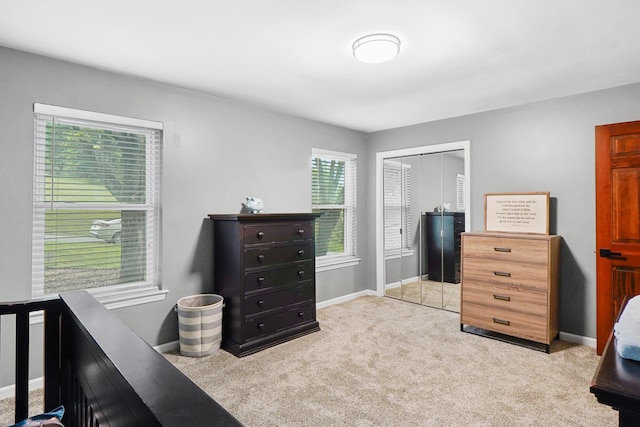 bedroom with baseboards, a closet, and light colored carpet