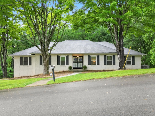 single story home featuring brick siding and a front yard