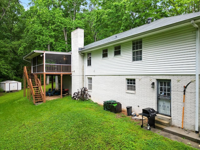 back of property with a yard, a storage unit, entry steps, a chimney, and a sunroom