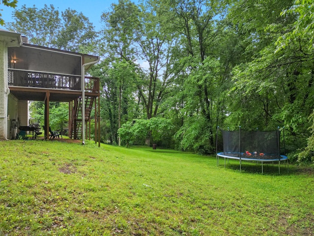 view of yard with a trampoline, stairway, and a deck