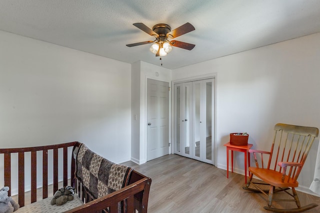 bedroom with light wood-style floors, baseboards, a ceiling fan, and a closet