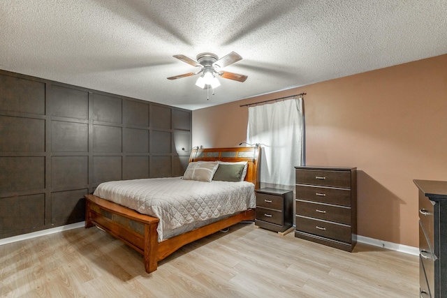 bedroom with a textured ceiling, baseboards, ceiling fan, and light wood finished floors