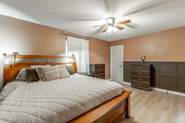 bedroom with ceiling fan, light wood-type flooring, and a textured ceiling
