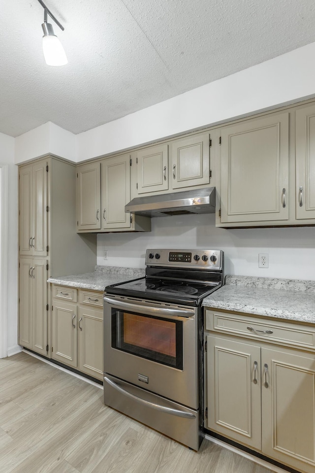 kitchen with a textured ceiling, light wood-style flooring, under cabinet range hood, and stainless steel range with electric cooktop