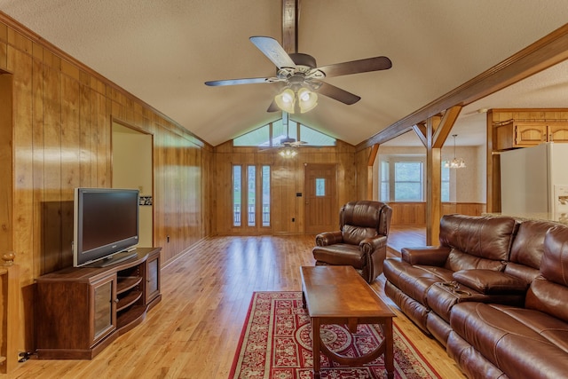 living room featuring a ceiling fan, wood walls, light wood-style flooring, and vaulted ceiling