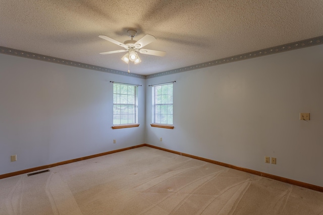 empty room featuring light colored carpet, a textured ceiling, a ceiling fan, baseboards, and visible vents