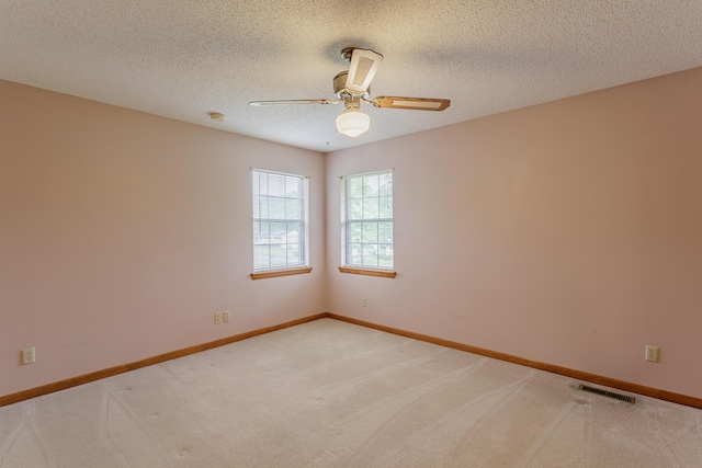 unfurnished room featuring a ceiling fan, a textured ceiling, light colored carpet, and visible vents