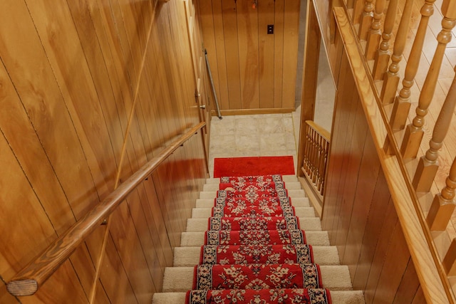 stairway featuring wood walls