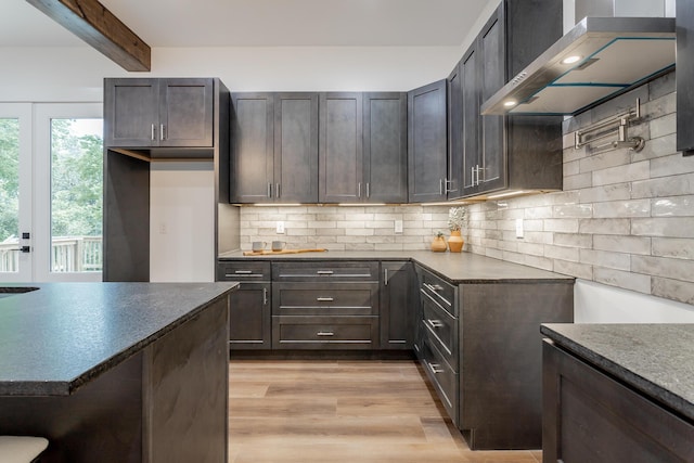 2111 Ivy St, Chattanooga, TN 37404 - kitchen with decorative backsplash, dark countertops, beamed ceiling, light wood finished floors, and wall chimney exhaust hood