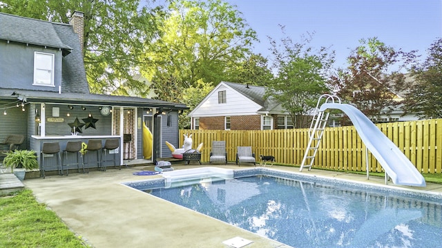 view of pool with a fenced backyard, outdoor dry bar, a water slide, and a fenced in pool