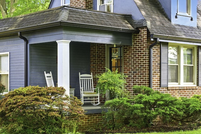 entrance to property with a porch and brick siding