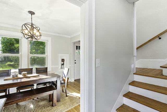stairs featuring a chandelier, ornamental molding, and wood finished floors