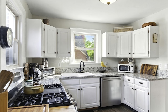 kitchen featuring stainless steel appliances, white cabinetry, and a sink