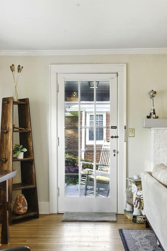 doorway with ornamental molding and wood finished floors