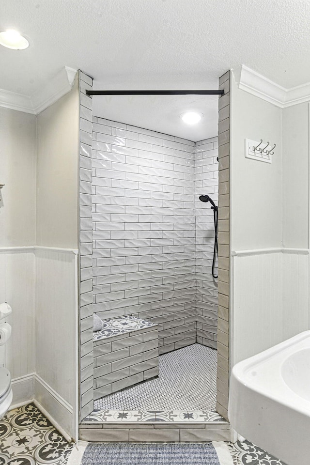 bathroom with toilet, ornamental molding, tile patterned flooring, and a stall shower