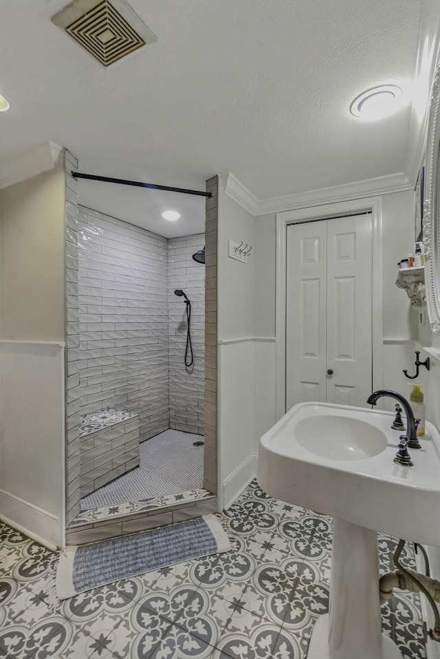 bathroom with crown molding, a stall shower, a textured ceiling, and visible vents