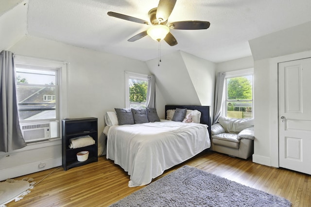 bedroom featuring light wood-style floors, multiple windows, cooling unit, and vaulted ceiling