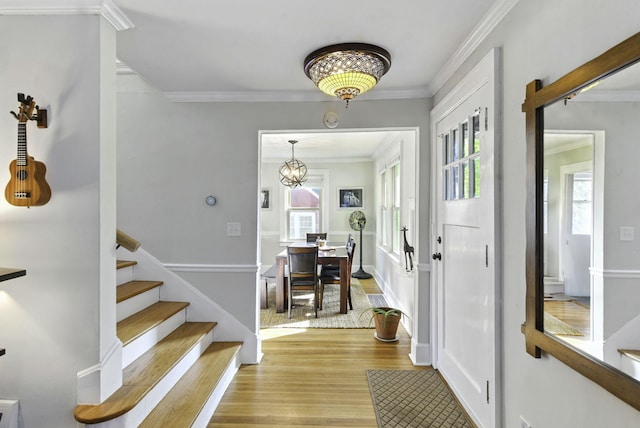 entrance foyer with ornamental molding, light wood-style flooring, stairs, and a healthy amount of sunlight