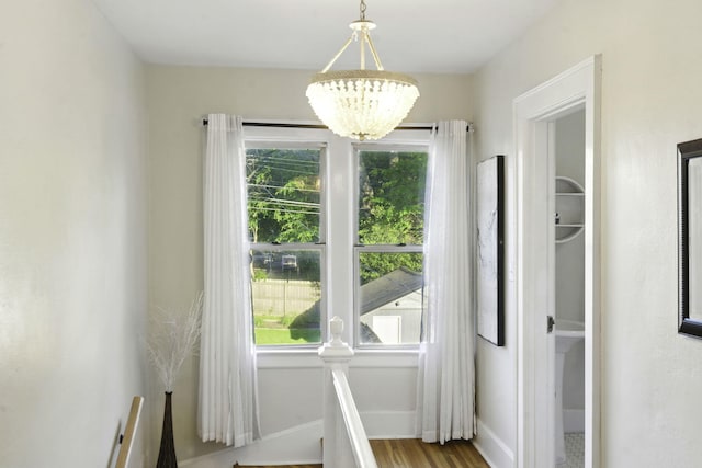 doorway to outside with a healthy amount of sunlight, baseboards, and an inviting chandelier