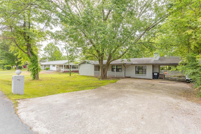 single story home with a front yard, a chimney, a porch, driveway, and a carport