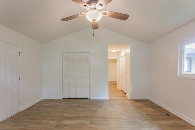 unfurnished bedroom featuring baseboards, lofted ceiling, light wood finished floors, and visible vents