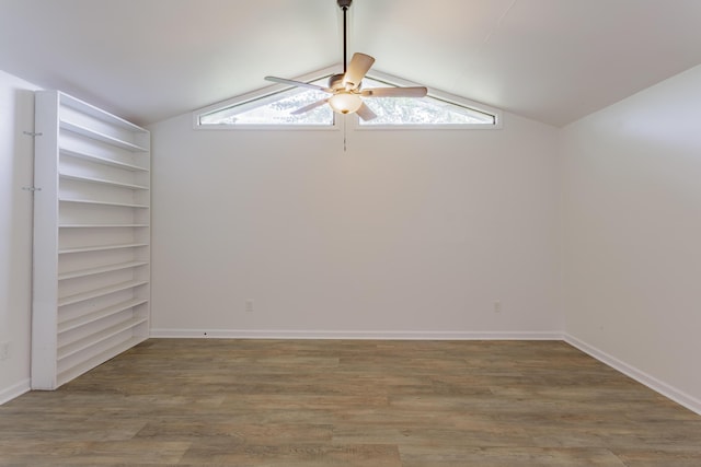unfurnished room featuring baseboards, ceiling fan, vaulted ceiling, and wood finished floors