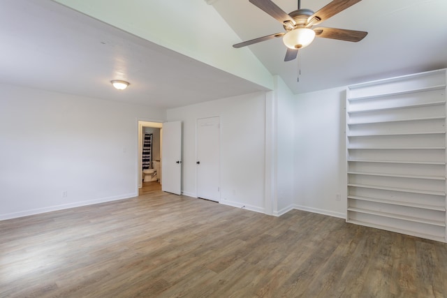 spare room featuring vaulted ceiling, baseboards, a ceiling fan, and wood finished floors