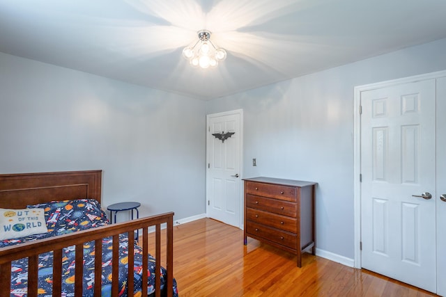 bedroom featuring baseboards, light wood-type flooring, and a notable chandelier