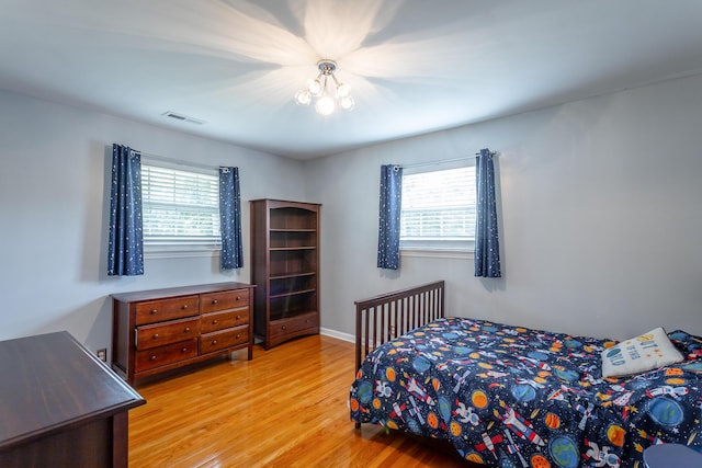 bedroom with multiple windows, wood finished floors, and visible vents
