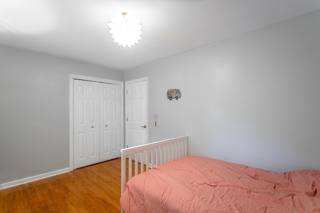 bedroom with baseboards, light wood finished floors, and a closet