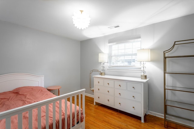 bedroom with baseboards, visible vents, and light wood-style floors