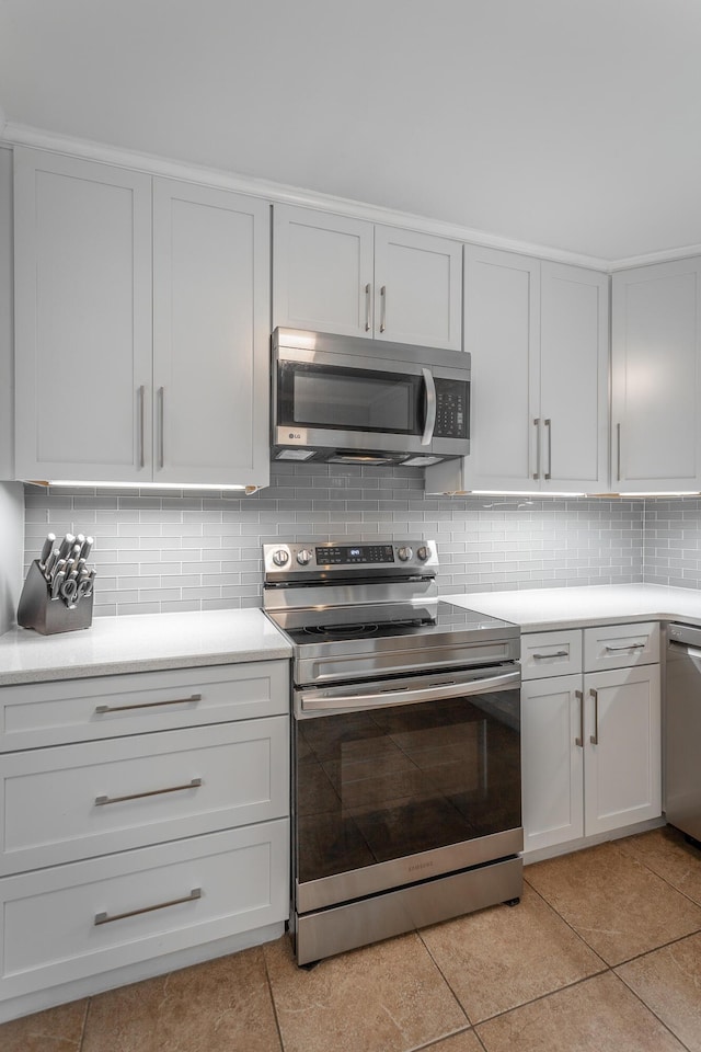 kitchen featuring decorative backsplash, appliances with stainless steel finishes, light countertops, light tile patterned floors, and white cabinetry