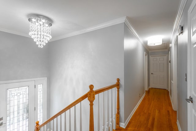 corridor featuring baseboards, wood finished floors, a notable chandelier, and an upstairs landing