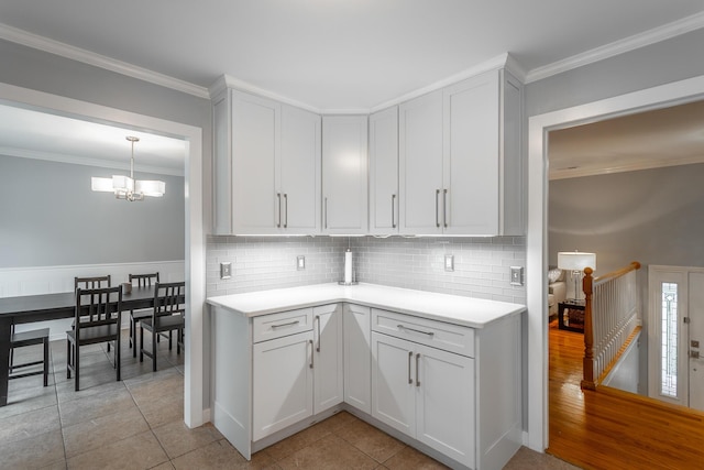 kitchen with ornamental molding, light countertops, tasteful backsplash, light tile patterned floors, and a notable chandelier
