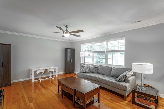 living area with crown molding, light wood-style floors, a ceiling fan, baseboards, and visible vents