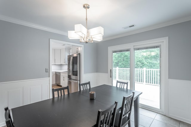 dining area with an inviting chandelier, wainscoting, light tile patterned floors, visible vents, and ornamental molding