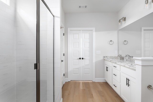 bathroom featuring wood finished floors, a shower stall, vanity, and baseboards