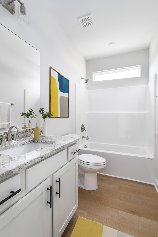 bathroom with toilet, shower / washtub combination, vanity, and wood finished floors
