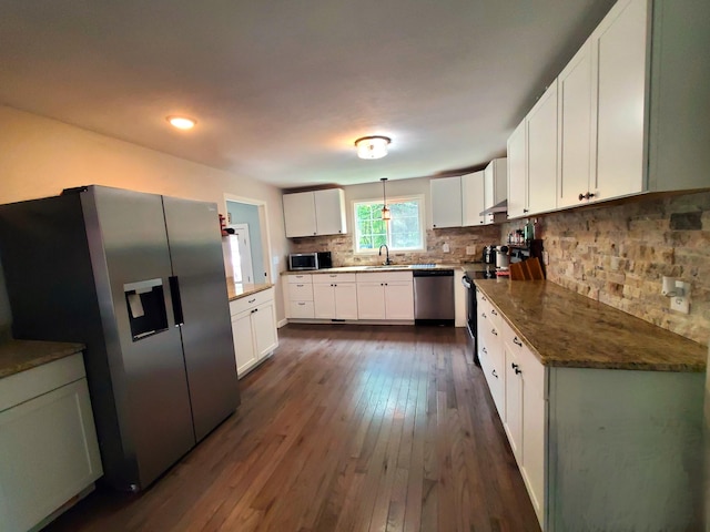 kitchen with a sink, stainless steel appliances, dark wood finished floors, white cabinetry, and decorative backsplash