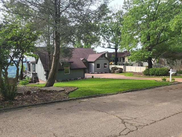 view of front facade featuring stairs, fence, driveway, and a front yard