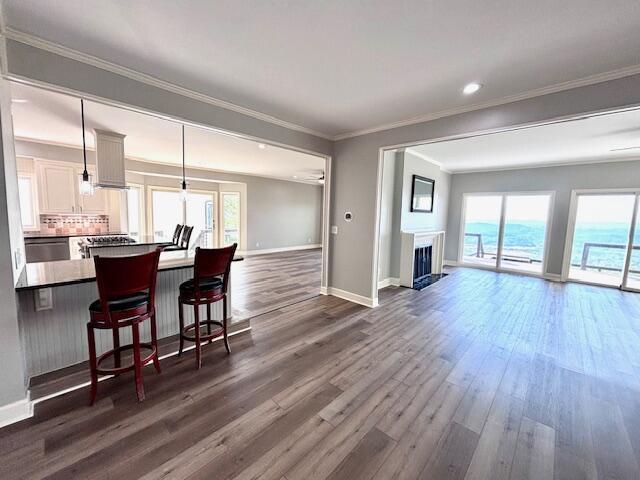 living room featuring baseboards, crown molding, dark wood-type flooring, and a fireplace