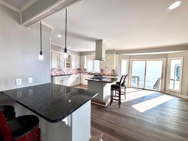 kitchen with crown molding, a breakfast bar, a peninsula, decorative backsplash, and wood finished floors