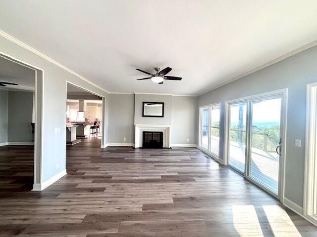 unfurnished living room featuring ornamental molding, wood finished floors, baseboards, ceiling fan, and a tile fireplace