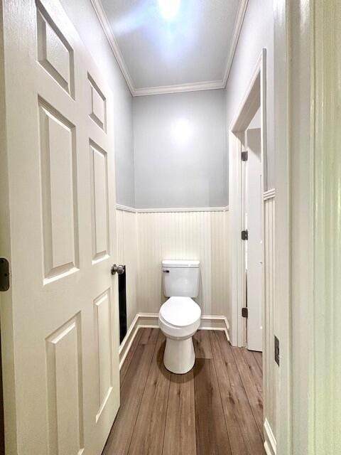 bathroom featuring crown molding, wood-type flooring, wainscoting, and toilet