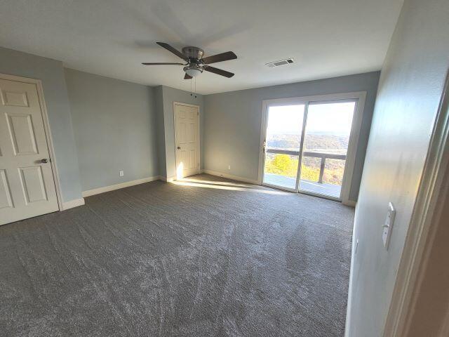 unfurnished room with dark colored carpet, baseboards, ceiling fan, and visible vents