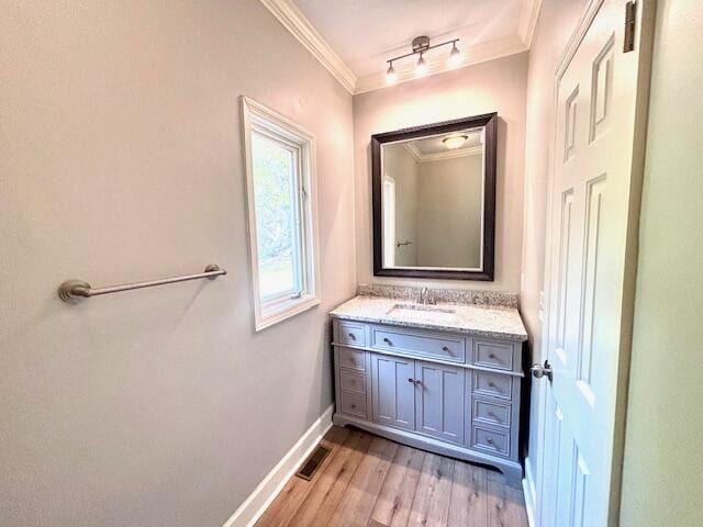 bathroom featuring crown molding, baseboards, wood finished floors, and vanity