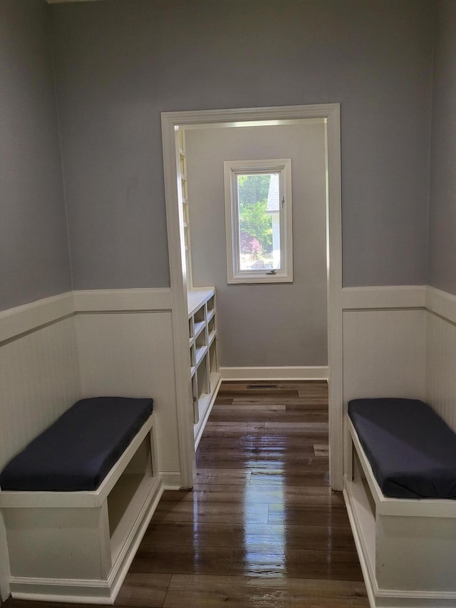 mudroom featuring a decorative wall, wainscoting, and dark wood-type flooring
